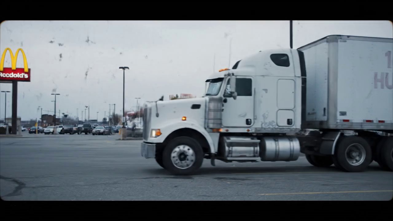 A large, weathered white semi-truck with a long tr...