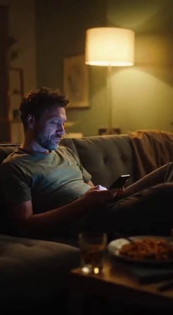[Sora 2] {
  "shot": {
    "composition": "Medium shot, 50 mm lens, man sitting alone on couch, phone scree... - Veo 3 AI video prompt thumbnail